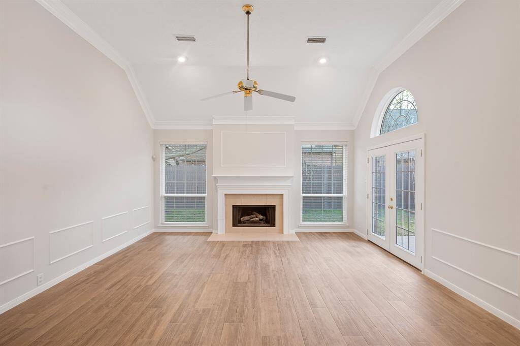 The family room covered with wood look tile floors has a wall of windows allowing the natural light to shine through