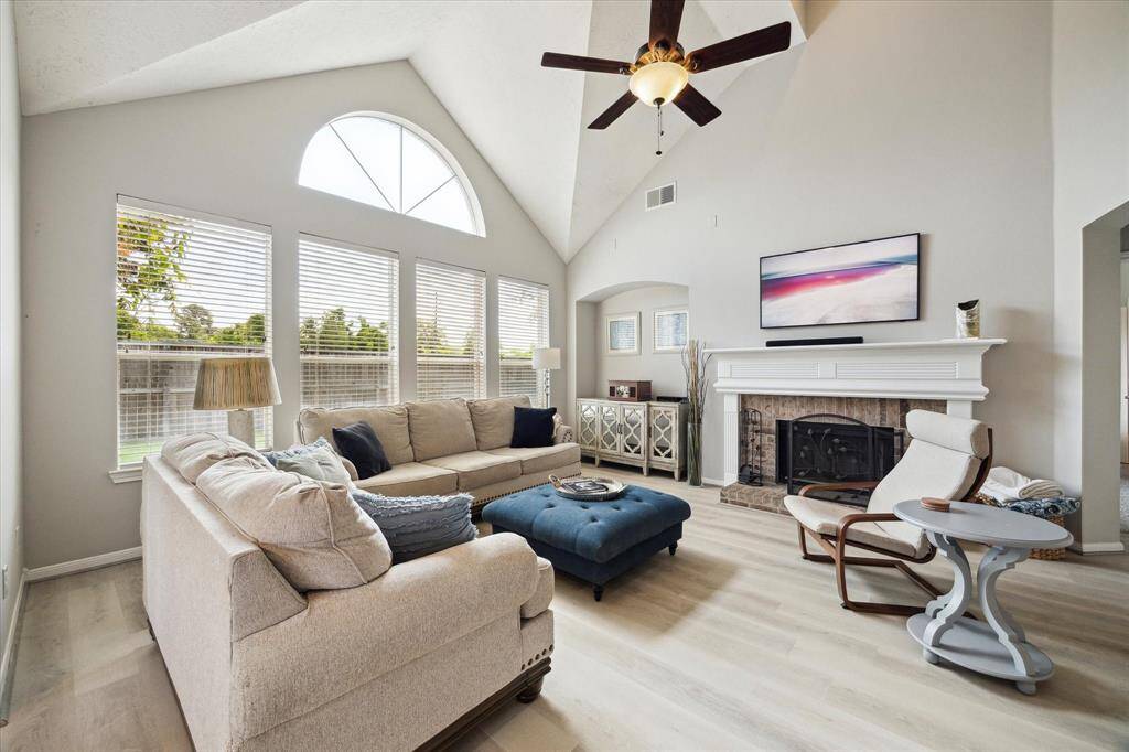 The living area is an elegant space with a soaring vaulted ceiling, a cozy gas fireplace, and a stunning wall of windows that flood the space with natural light.