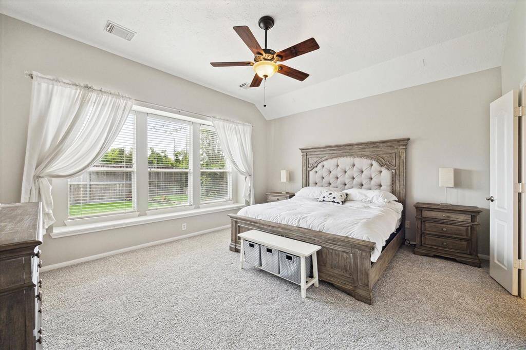 Experience tranquility in the spacious primary bedroom with expansive windows offering stunning views of the private backyard.