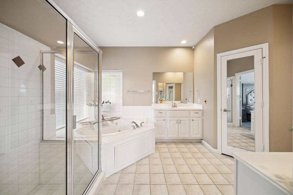 Escape to luxury in the primary bath with dual vanities, a spacious standing shower, and a relaxing jetted tub.