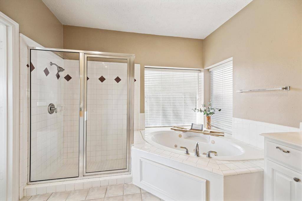 Experience ultimate relaxation in this bright bathroom featuring a jetted tub and large window for natural light.