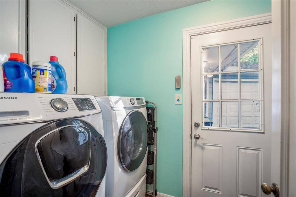 The utility room with cabinets above the washer/dryer, and shelving on the opposite side of the room for addtional storage.