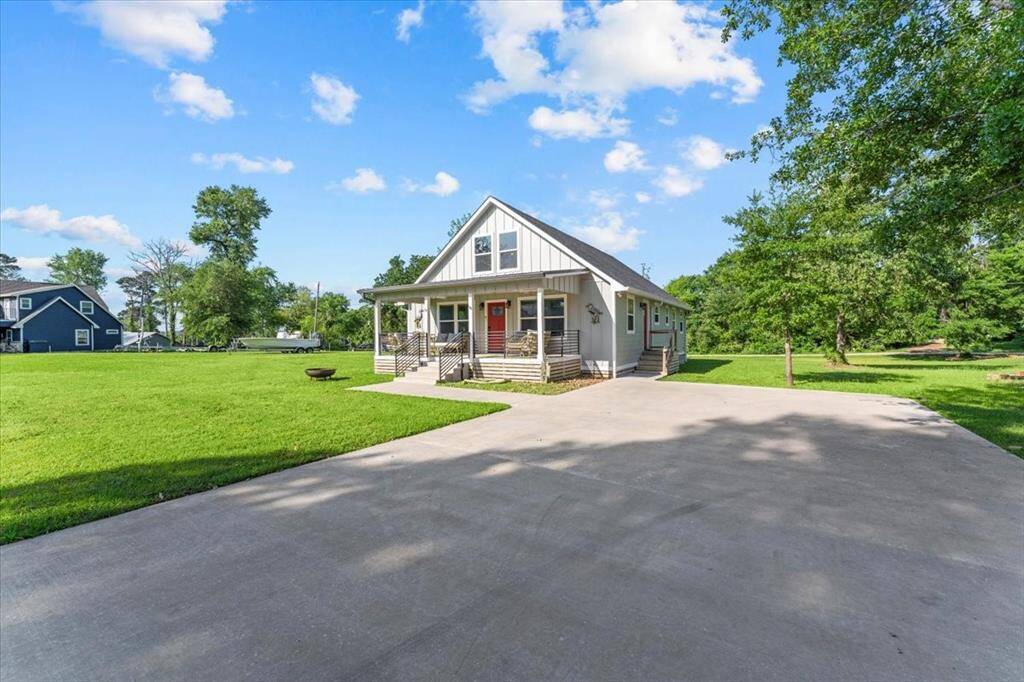 Charming single-story home with a spacious front yard and a long driveway. The house features a welcoming front porch, modern exterior, and is surrounded by lush greenery, perfect for privacy and outdoor activities.