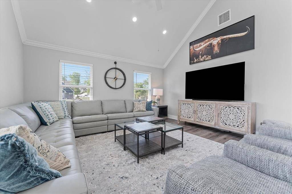 This spacious living room features high ceilings, large windows for natural light, and a modern, neutral color scheme with window treatments!