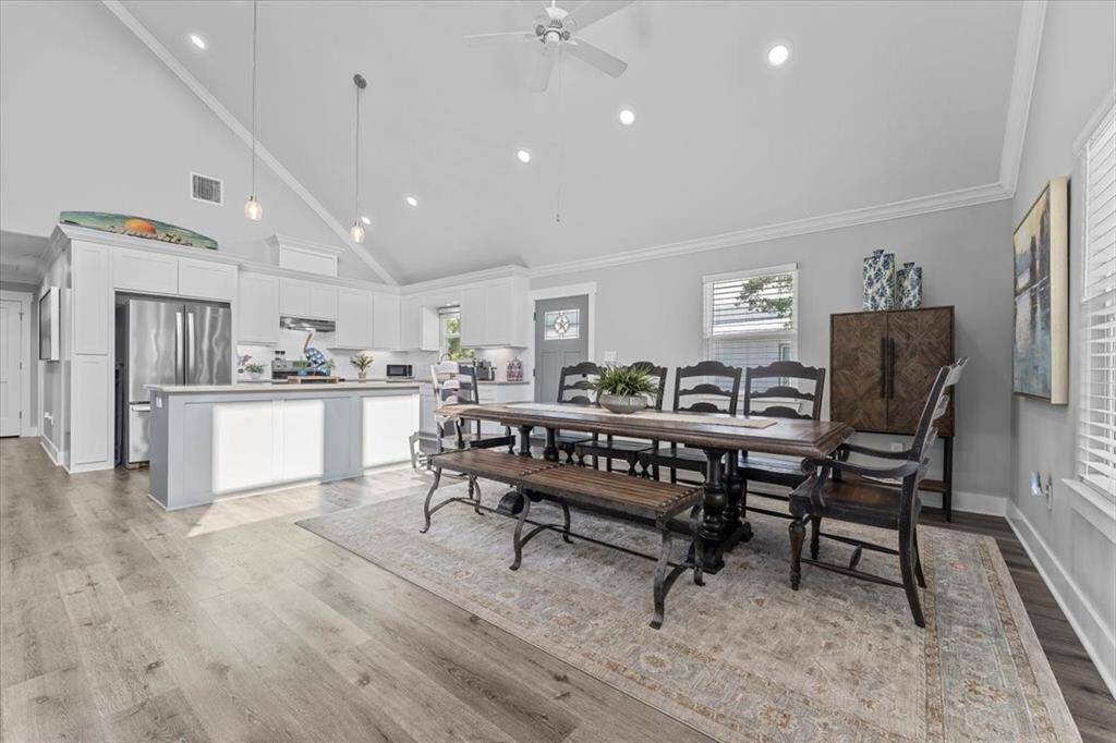 What a beautiful spacious, open-concept kitchen and dining area with high ceilings and abundant natural light. The kitchen features modern cabinetry, stainless steel appliances, and a large island. The dining area is large enough for ample seating. The room's neutral tones and elegant finishes create a welcoming, contemporary atmosphere.
