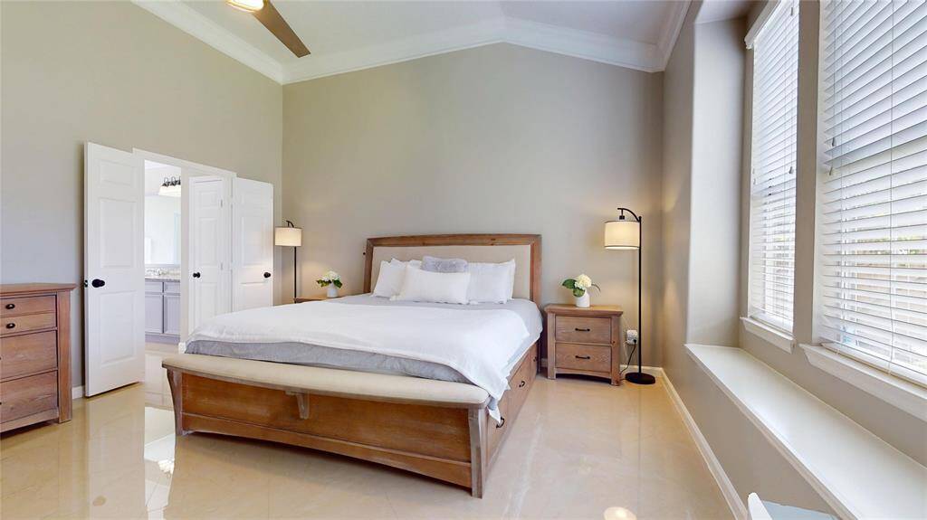 The Primary Bedroom also features large windows let in ample natural light, and there's an en-suite bathroom visible through double doors.