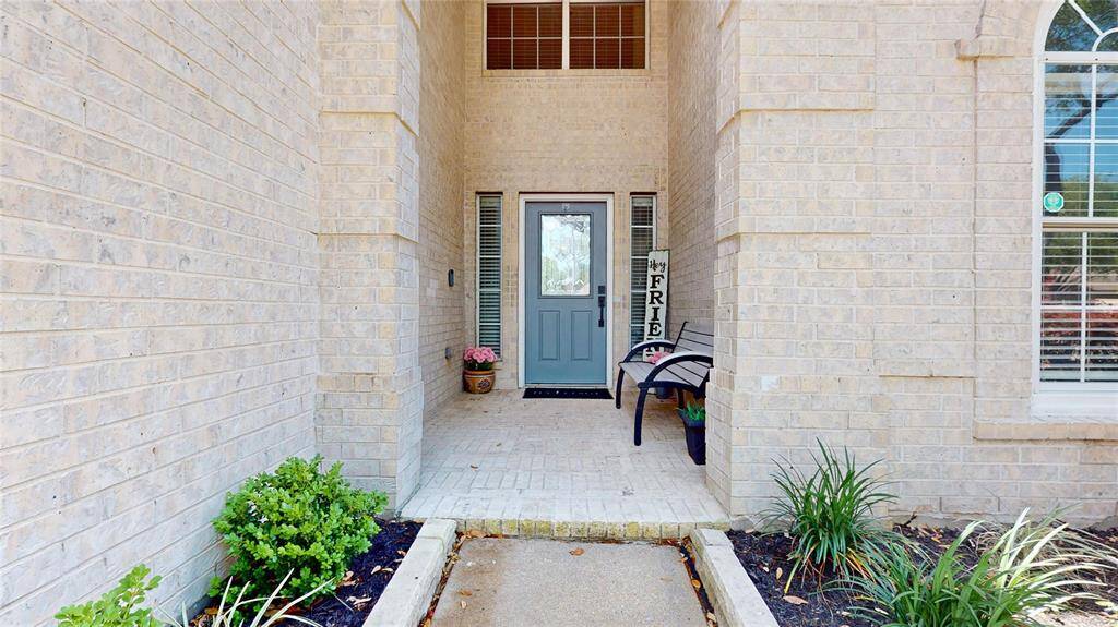 Welcoming front entrance with a cozy porch, featuring a modern door, brick and inviting landscaping.
