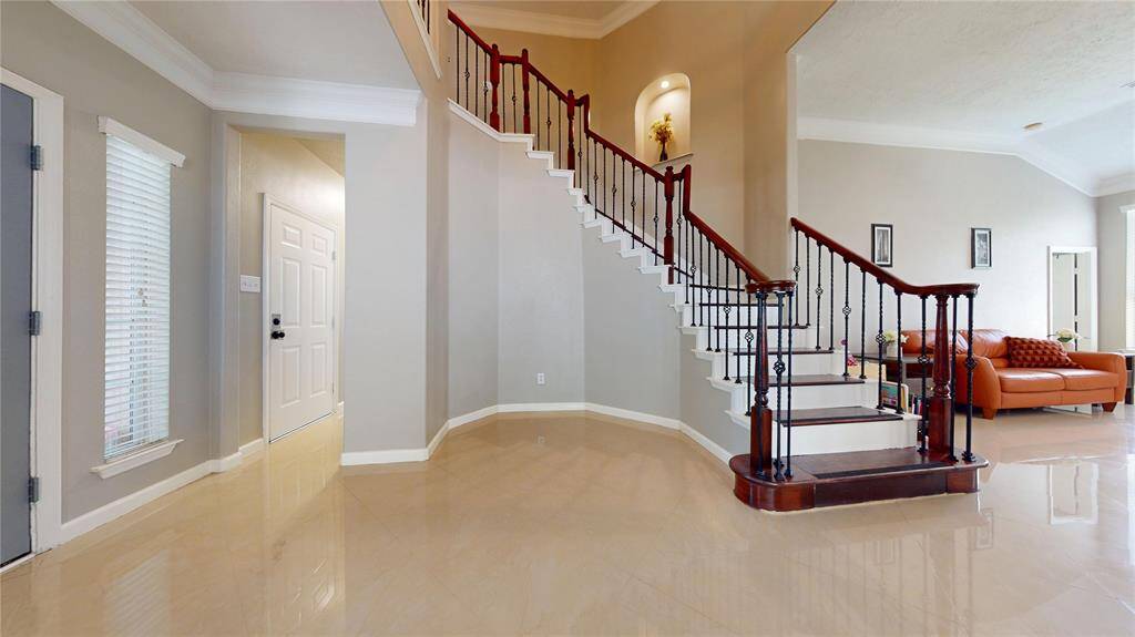 This photo showcases a grand staircase featuring elegant dark wood and wrought iron railings. The open layout seamlessly connects to a cozy living area.