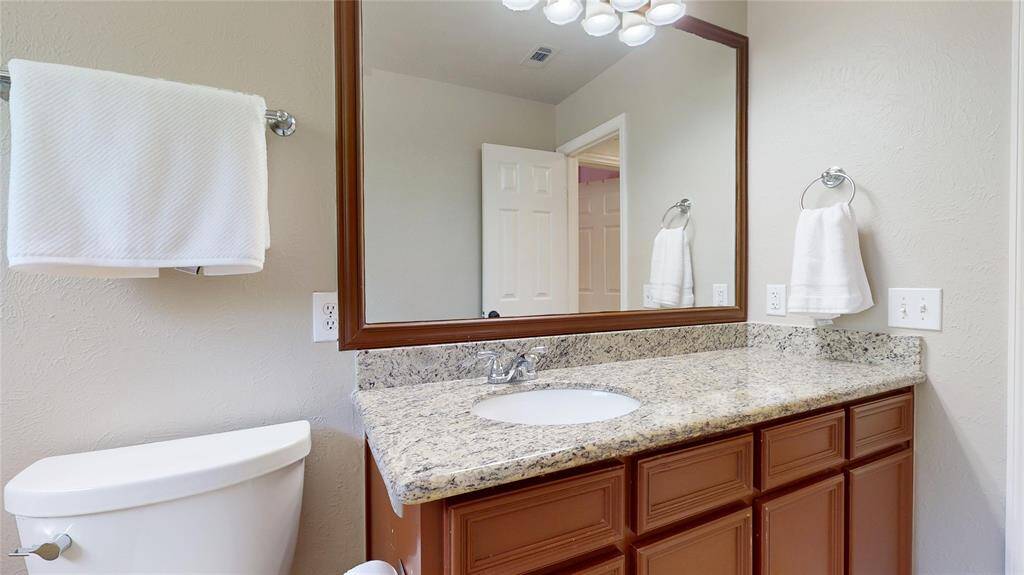Guest Bathroom #2 also features a large mirrow and granite countertop.