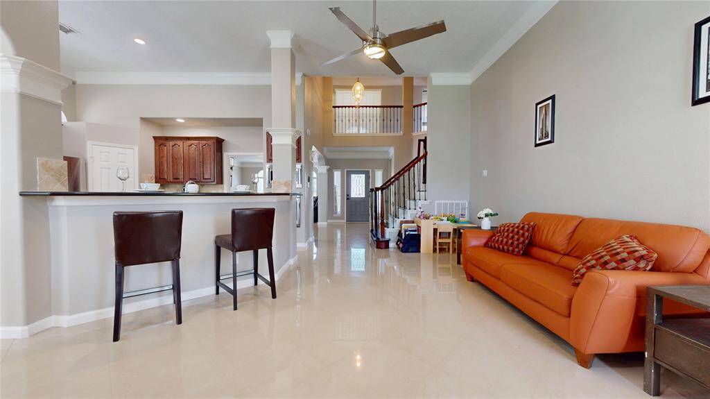 The living area features a high ceiling and an open floor plan, with elegant tile flooring.