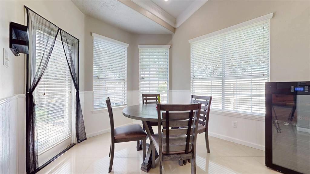 Bright breakfast area featuring large windows with blinds for natural light, and a glass door leading outside.
