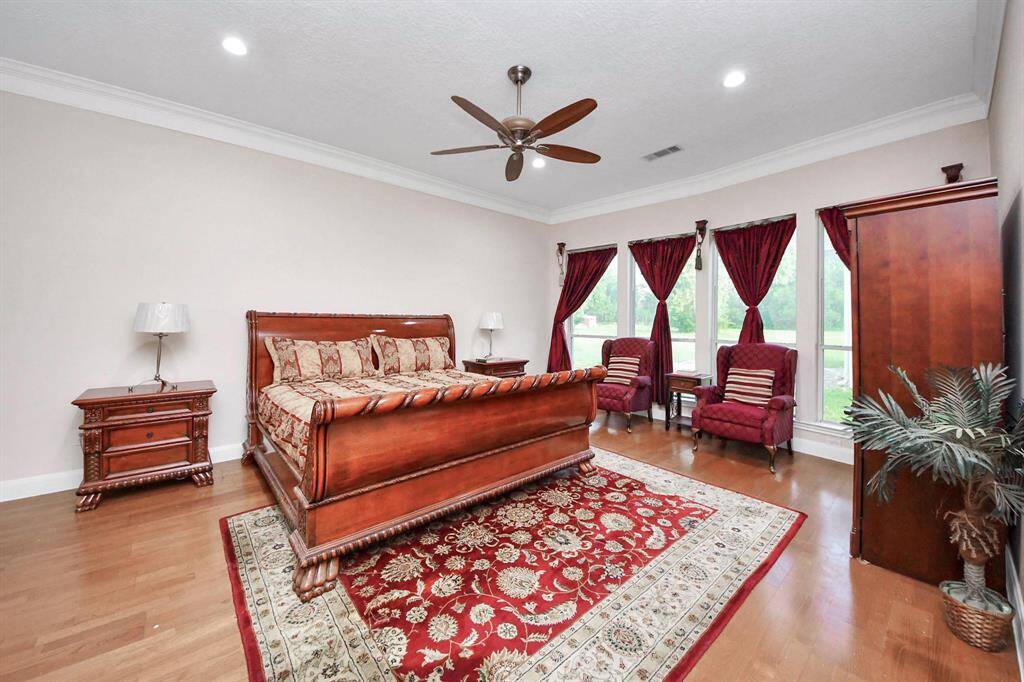 his spacious bedroom features large windows that fill the room with natural light and offer peaceful views of the surrounding property, creating a serene atmosphere perfect for unwinding at the end of the day.