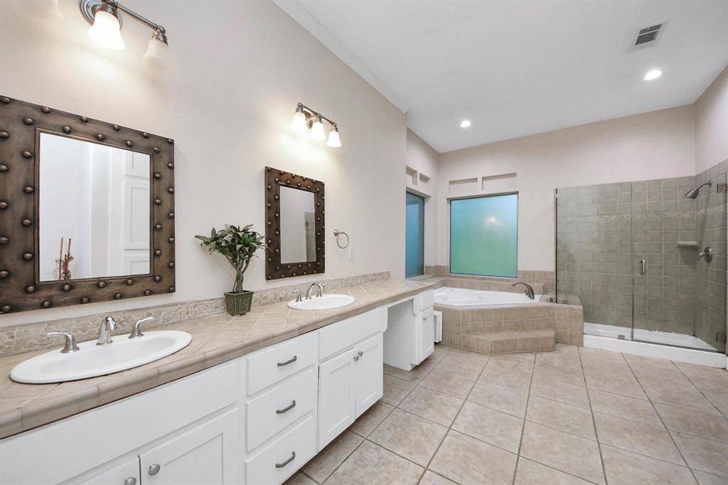 It includes dual sinks with ample counter space and storage, a deep soaking tub for a spa-like experience, and a separate walk-in shower with modern finishes.