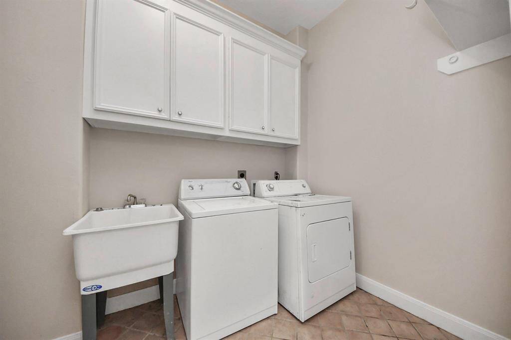 The indoor laundry room is both functional and spacious, featuring a built-in utility sink, custom cabinetry, and ample space for storage and organization. Whether tackling daily laundry or managing household chores, this well-designed room makes the task easier and more efficient.