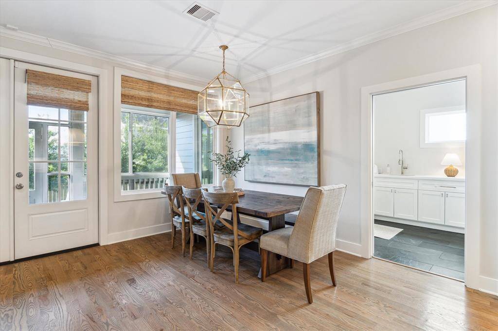 Walls of windows fill the dining area with natural light, while woven shades and a geometric pendant add warmth and texture. Tucked just off the kitchen and living space, it offers a cozy yet elevated spot for daily meals or special gatherings.