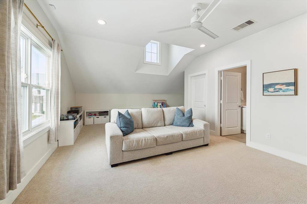 Tucked beneath vaulted ceilings, the upstairs game room offers a versatile space for play, work, or lounging. A dormer window adds architectural interest and extra natural light. The space features a full bathroom and closet space.