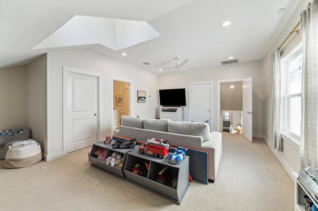 This alternate angle of the upstairs game room showcases its flexibility, with multiple access points to storage and additional rooms. Large windows brighten the space, while the open layout is ideal for media, play, or a second living area. Neutral tones and plush carpet enhance the cozy, multipurpose design.