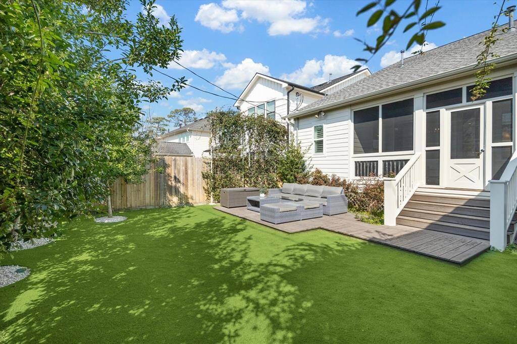 A final look at the backyard showcases the expansive turf lawn and the seamless flow from the screened-in porch to the open-air deck. Mature landscaping frames the yard, creating a private and polished outdoor setting ideal for gatherings or everyday enjoyment.