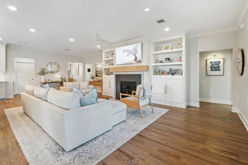 This alternate angle highlights the seamless flow between the living area and surrounding spaces. Custom built-ins and a sleek gas fireplace anchor the room, while wide-plank wood floors and soft, neutral tones enhance the open and inviting layout.