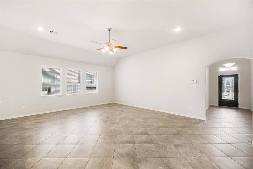 Tile flooring continues into the open and spacious family room, which features recessed lighting, a ceiling fan with a light fixture, and abundant natural light for a bright and welcoming atmosphere.