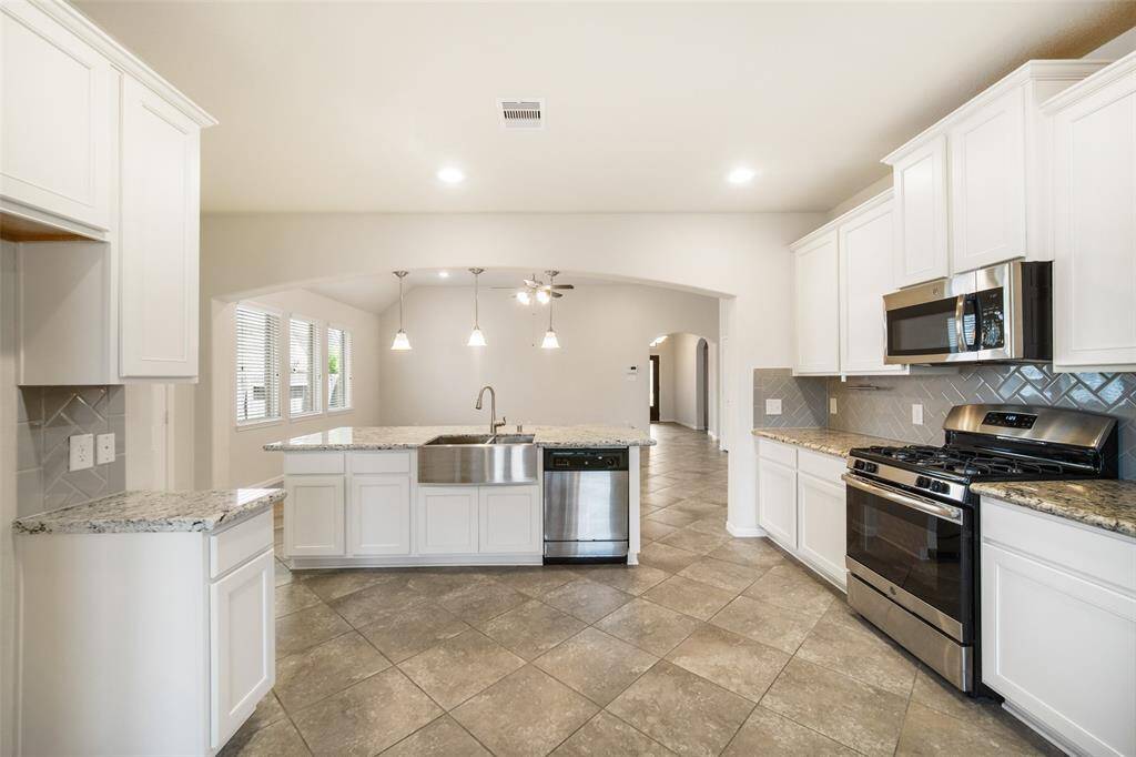 The kitchen is equipped with stainless steel appliances, a stylish backsplash, and ample drawers and cabinets for your kitchen essentials, all finished with crown molding that enhances the overall beauty of the space.