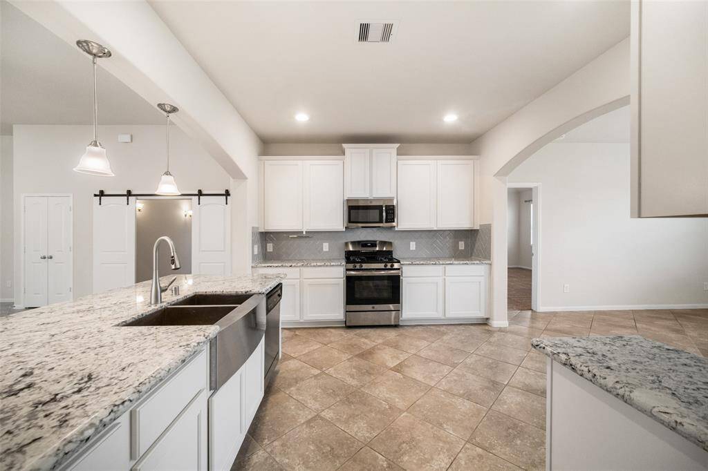 This kitchen view showcases the elegant stainless steel drop-in sink, paired beautifully with sleek granite countertops featuring a modern flat edge.