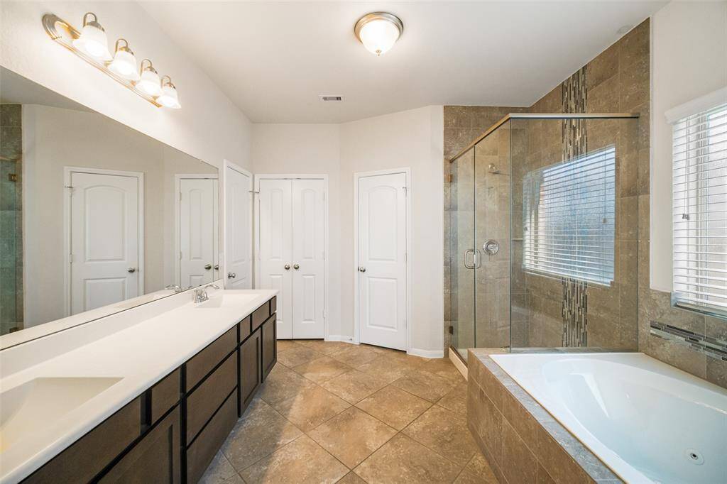The primary en-suite features dual sinks with cabinet and drawer space for all your bathroom essentials, a walk-in closet, a relaxing soaking tub, and a separate glass-enclosed shower.