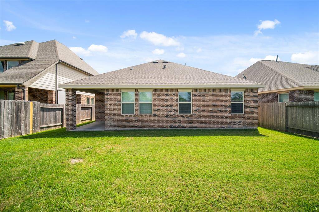 The backyard features a covered patio and green space, perfect for playing, gardening, or simply enjoying the outdoors.