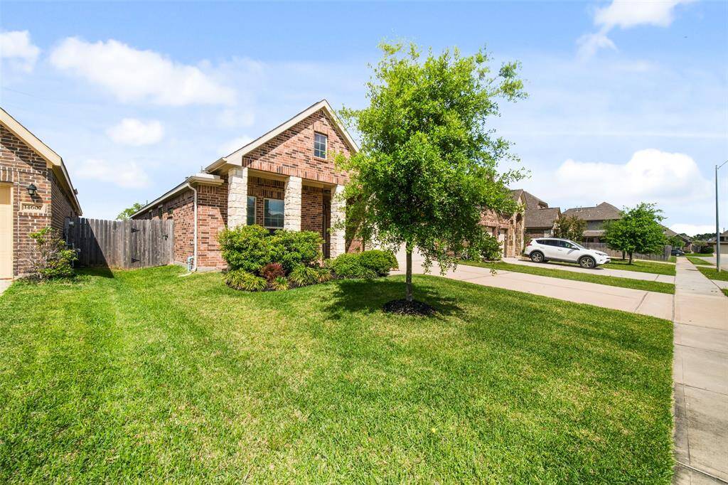 This front side view highlights the landscaped yard, flowerbeds, and the home's brick and stone exterior.