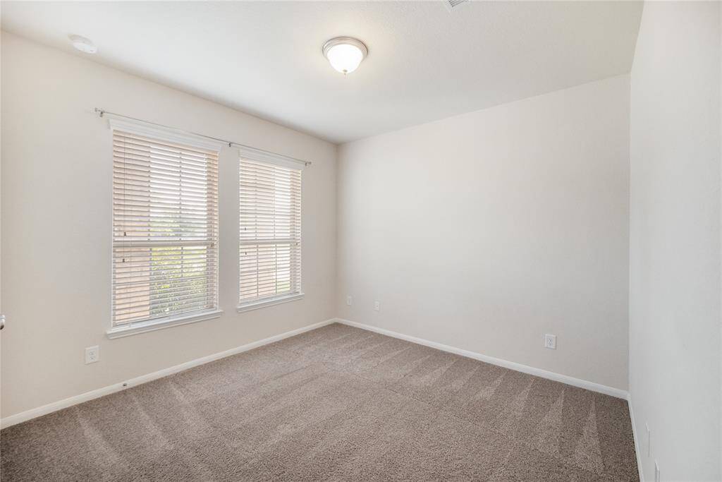 One of two secondary bedrooms, this front-facing room offers views of the front yard, a closet, cozy carpet flooring, and a window that fills the space with natural light.
