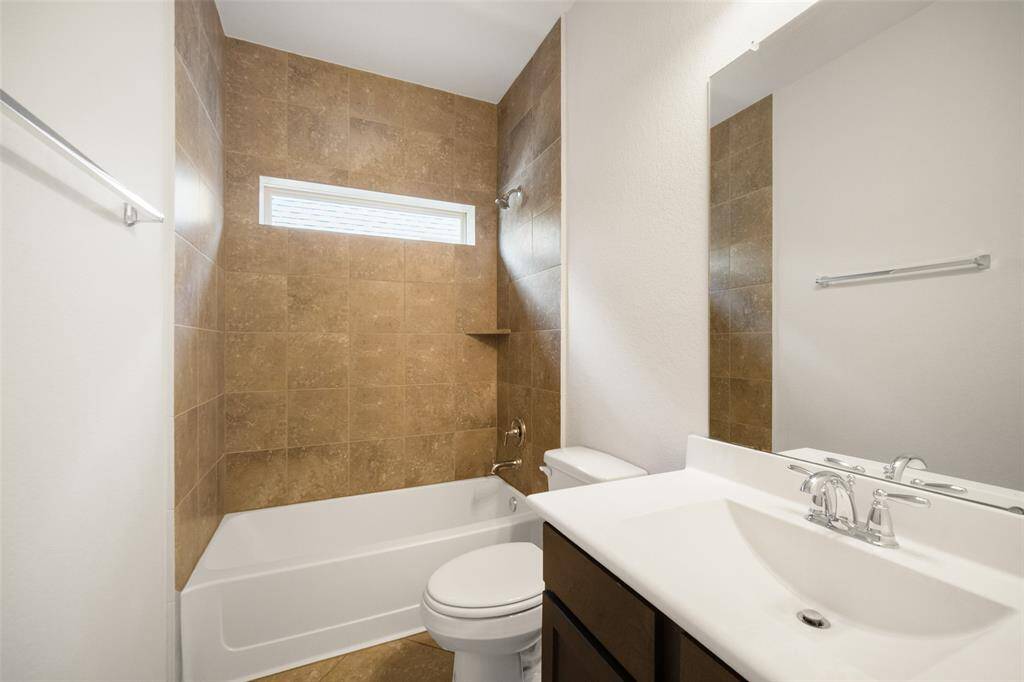 The secondary full bathroom is conveniently situated between the two secondary bedrooms and features a single-sink vanity with cabinet storage, along with a shower/tub combo.