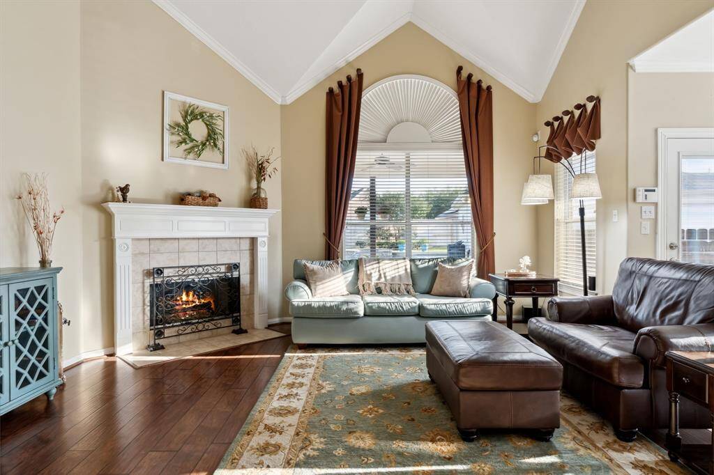 This inviting living room features high vaulted ceilings and a cozy fireplace. Natural light pours in through large windows.