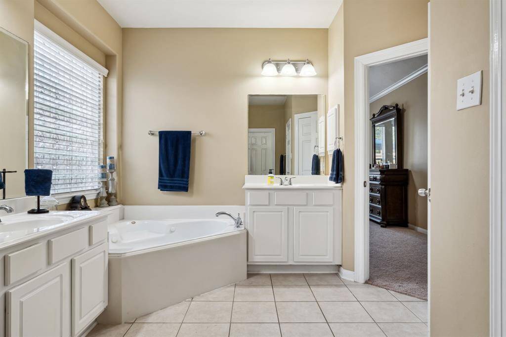Corner jetted tub with large window above.