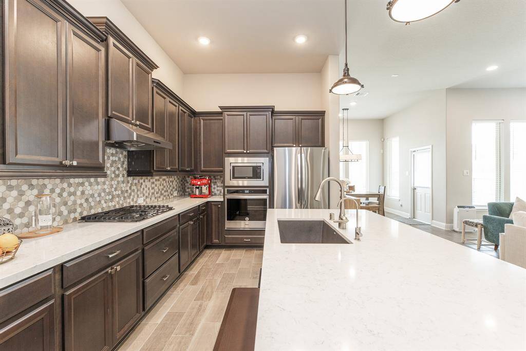 This modern kitchen features stunning large island, stainless steel appliances and gas stove with a stylish backsplash.