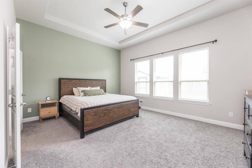 Bright and spacious primary bedroom located on the first floor, featuring high ceilings, windows to bring in the natural light and a ceiling fan for your comfort