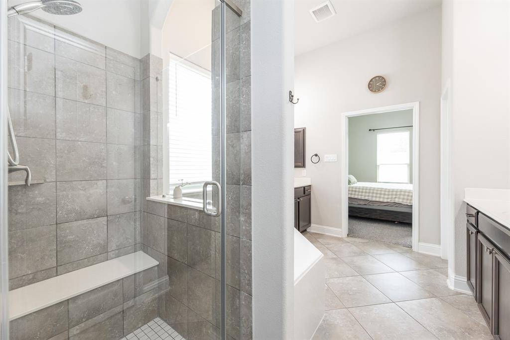 This modern primary ensuite bathroom featuring a large glass-enclosed shower