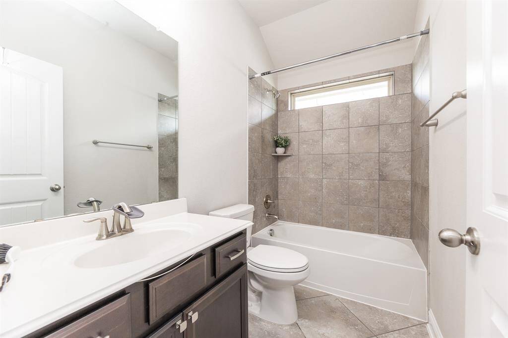 Upstairs full bathroom features a clean design with a tiled shower and bathtub, a large mirror.