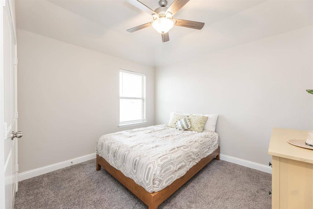This 4th bedroom upstairs features neutral walls, a ceiling fan, a window for natural light.