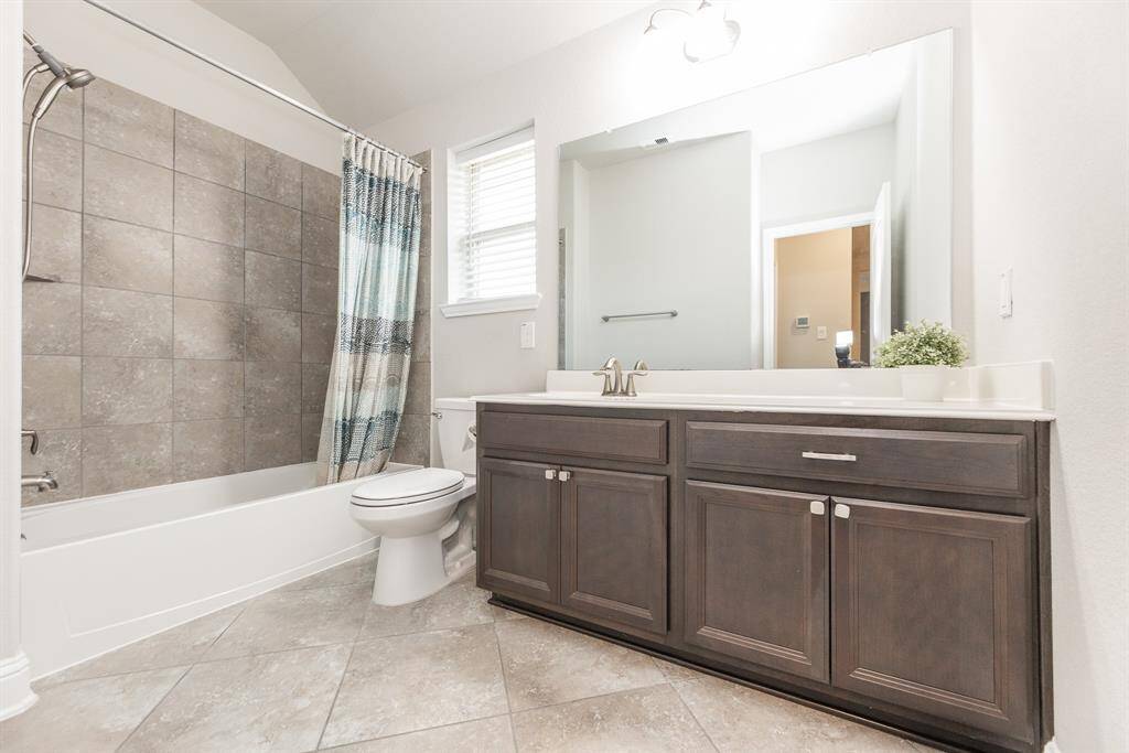 This upstairs full bathroom features a clean design with a tiled shower and bathtub, a large mirror, and extra cabinets.