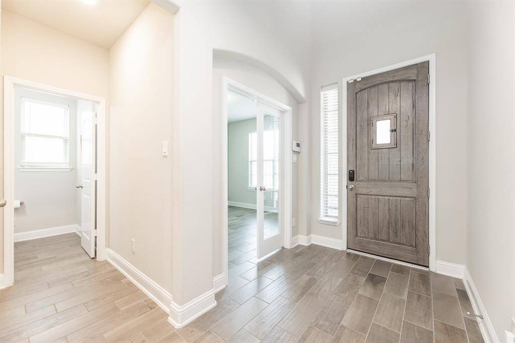 Entryway features a wooden door, wood-look tile flooring