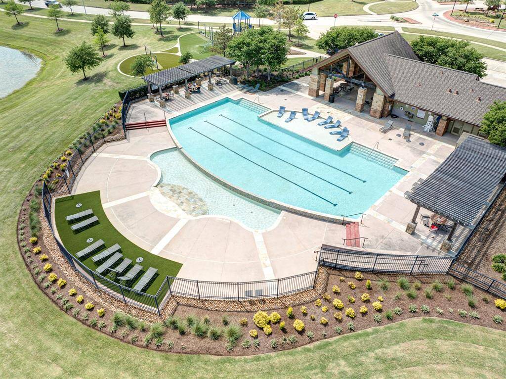 Community pool area with a covered seating space, surrounded by trees and a pond, creating an inviting neighborhood environment.
