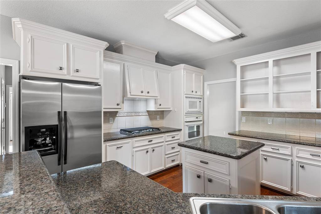 Granite, island kitchen with stainless appliances looking towards formal dining.