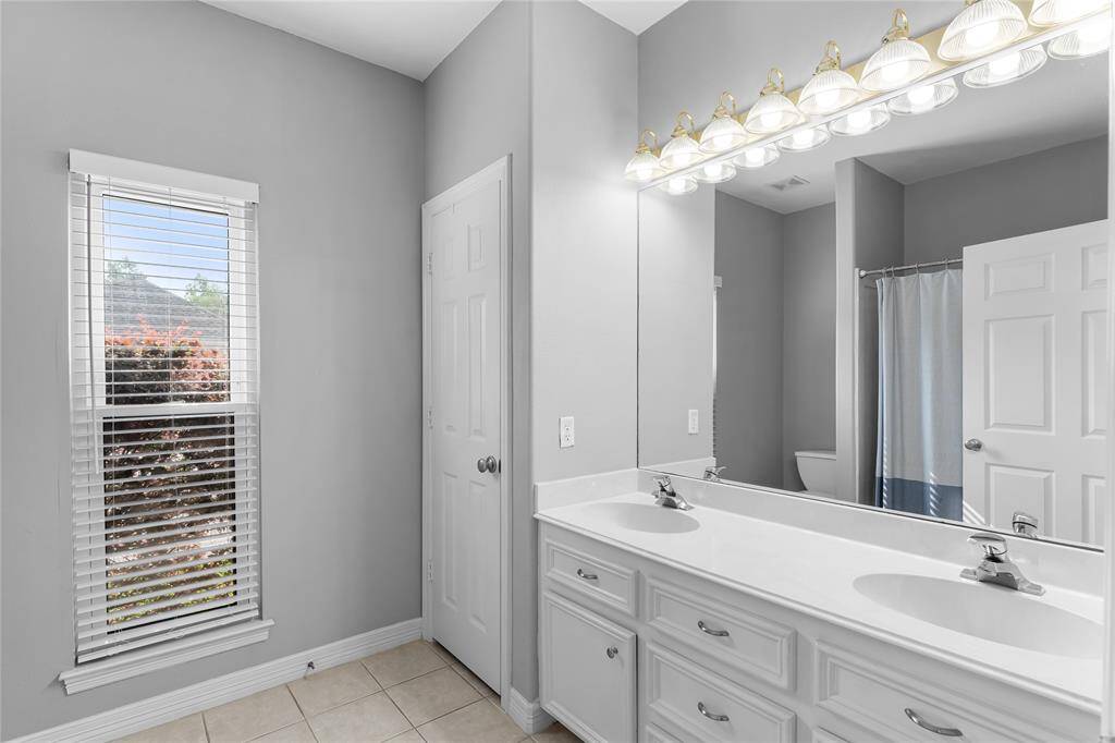 Full en-suite bath in second primary bedroom downstairs with dual sinks.