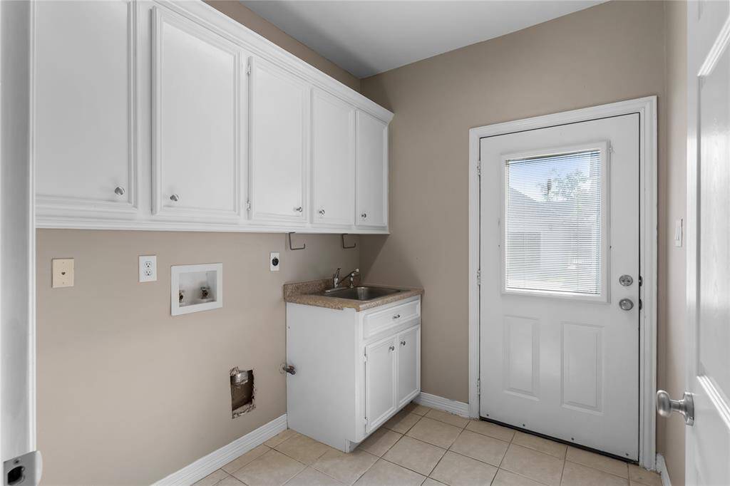 Tons of room in the laundry room with cabinet storage, sink and access to backyard!