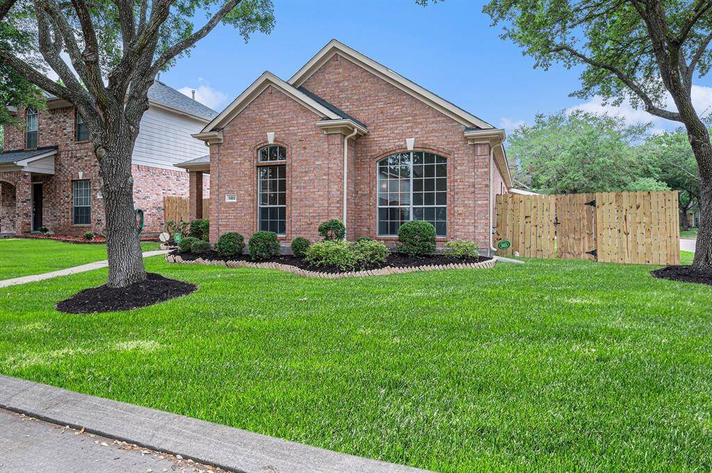 Charming single-story brick home with well-manicured lawn and mature trees. Features include large front windows, neat landscaping, and a wooden privacy fence. Located in a peaceful neighborhood.