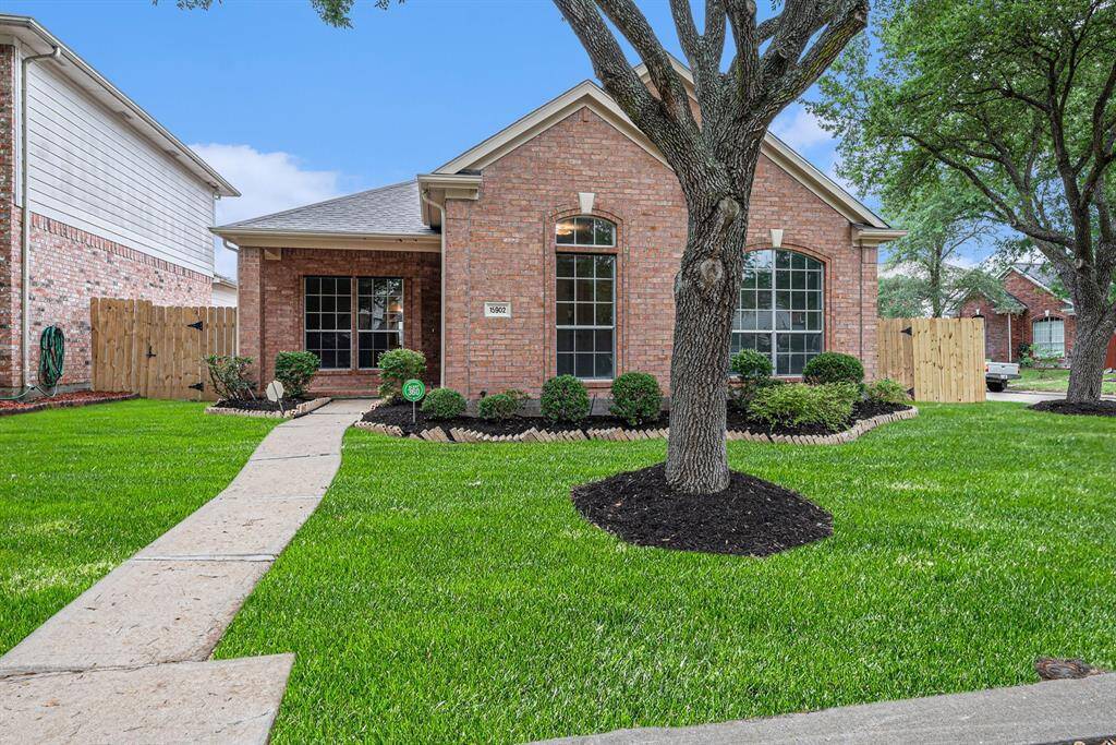 Charming brick home with a well-maintained front yard, featuring lush greenery and a mature tree. The inviting path leads to a cozy entrance, flanked by large, arched windows. Ideal for a welcoming, family-friendly neighborhood.