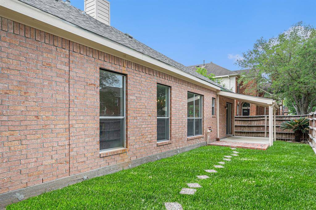 Charming brick exterior with a well-maintained backyard featuring a small patio and stepping stone path. Ideal for outdoor relaxation.