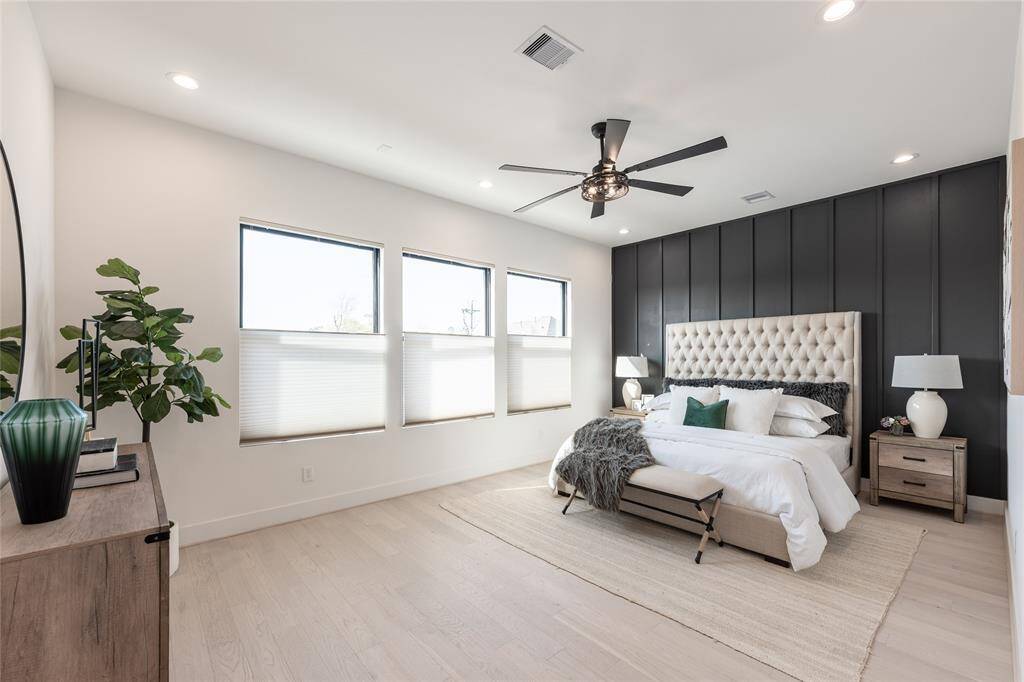 The primary bedroom features oversized windows that invite natural light, enhancing the serene and airy ambiance.