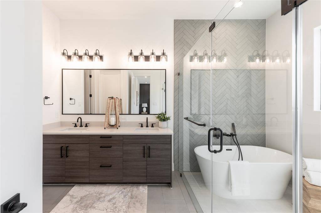 A spa-like oasis, the primary bath features a striking freestanding soaking tub and an expansive glass-enclosed shower.