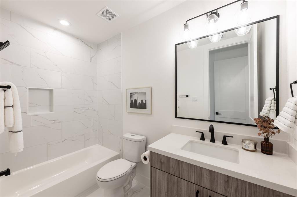 A blend of modern convenience and timeless design, this secondary bath features a sleek shower-tub combo and high-end finishes.